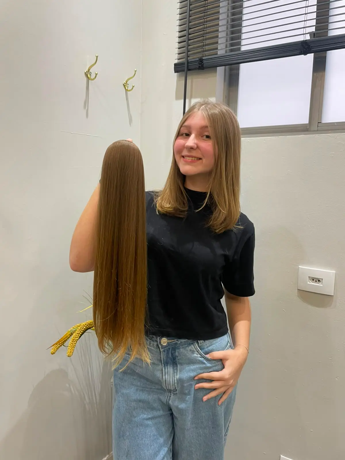 Cliente segurando cabelo loiro natural após o corte em Curitiba